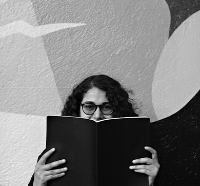 Woman with glasses holding up a book